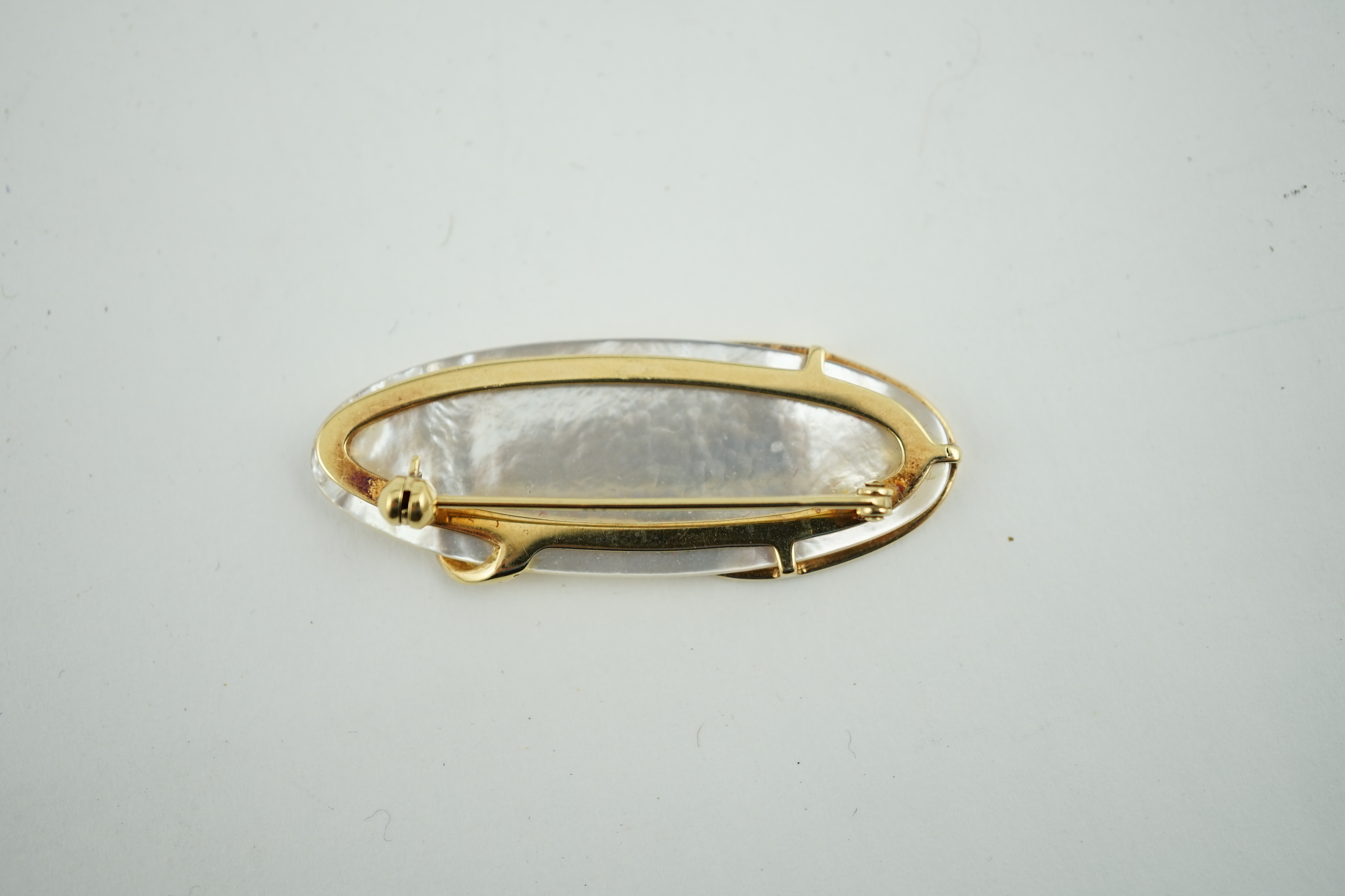 A modern stylish 18ct gold and diamond chip mounted mother of pearl brooch